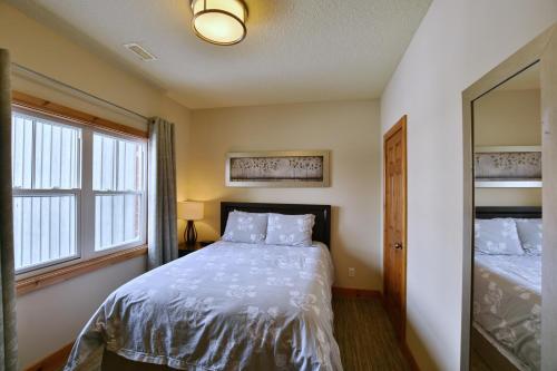 a bedroom with a bed and two windows and a mirror at The Blue Escape Blue Mountain Chalet in Blue Mountains