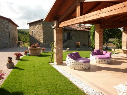 un patio con sillas moradas en un césped verde en Agriturismo Prato degli Angeli en Sassoleone