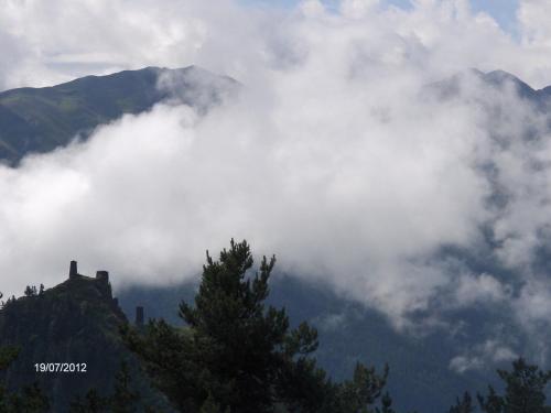 a mountain obscured by clouds with a tree in the foreground at Guest House Mirgvela in Omalo