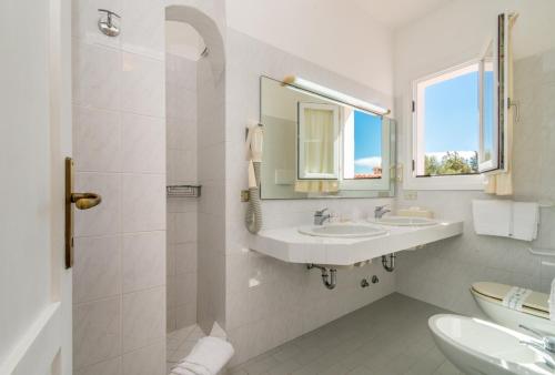 Baño blanco con lavabo y espejo en Hotel 3 Botti en Baja Sardinia