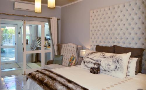 un osito de peluche sentado en una cama en un dormitorio en 1AA Wilhelmina Luxury Suites en Franschhoek