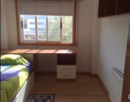 a bedroom with a desk in front of a window at A Coruña al lado de la playa in Bastiagueiro