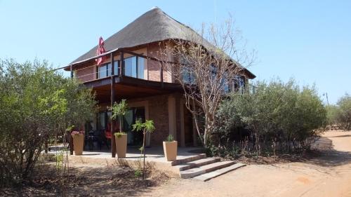 a thatch roofed house with a thatched roof at Baobab - NUDE - SunEden Family Naturist Resort in Pretoria