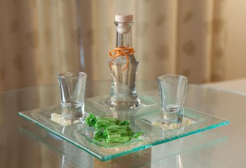 a glass bottle and two glasses on a glass table at Central Hotel in Athens