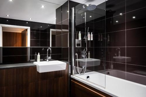 a bathroom with a sink and a shower and a tub at Aparthotel Adagio London Brentford in Brentford