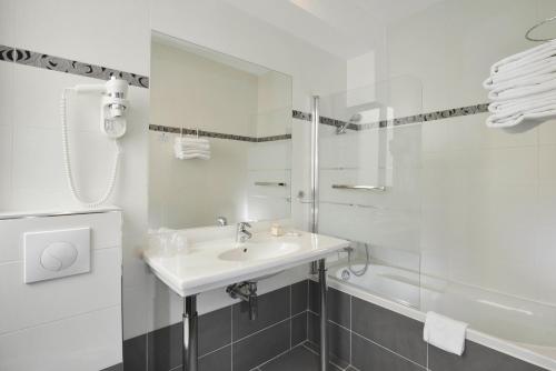 a white bathroom with a sink and a shower at Carladez Cambronne in Paris