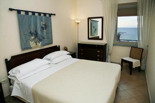 a bedroom with a bed and a window with the ocean at Palazzetto Florio 1810 in Santa Maria di Castellabate