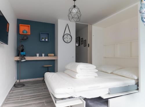 une chambre avec un lit et une horloge au mur dans l'établissement Le Magellan, à La Grande Motte