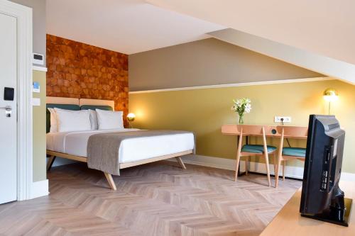 a bedroom with a bed and a desk and a tv at My Story Hotel Tejo in Lisbon