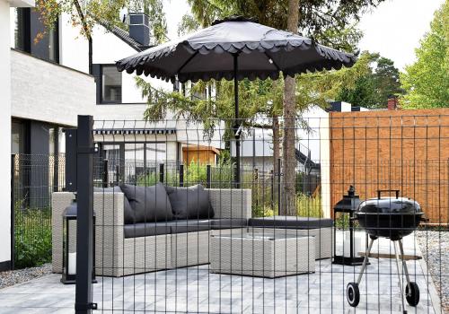a patio with a couch and an umbrella and a grill at Chill&Sun in Łukęcin