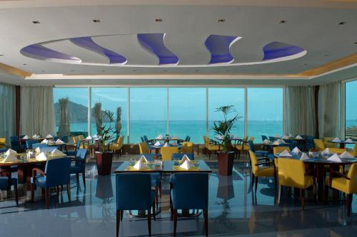 a restaurant with tables and chairs and a view of the ocean at Oceanic Khorfakkan Resort & Spa in Khor Fakkan