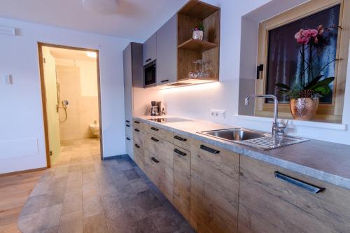 a large kitchen with a sink and a window at Mair am Anger-Appartments in Riscone