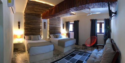 a hotel room with two beds and a couch at Tierra Maya Hotel Spa & Sanctuary in Bacalar