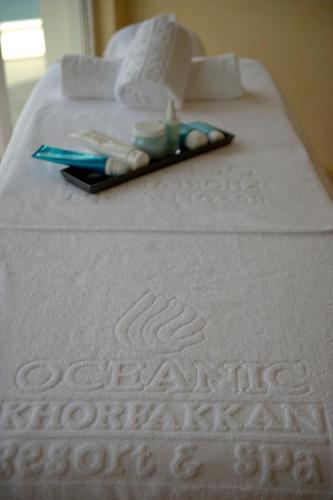 a close up of a white bed with a book at Oceanic Khorfakkan Resort & Spa in Khor Fakkan