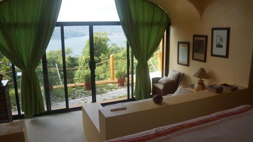 a living room with a large window with green curtains at preciosa casa que ve al pacifico in Zihuatanejo