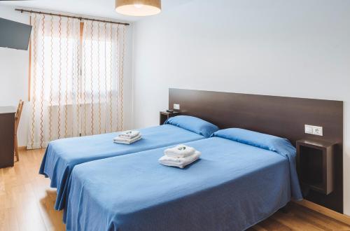 a bedroom with two towels on a blue bed at APARTAMENTOS CASAS NOVAS in Silleda
