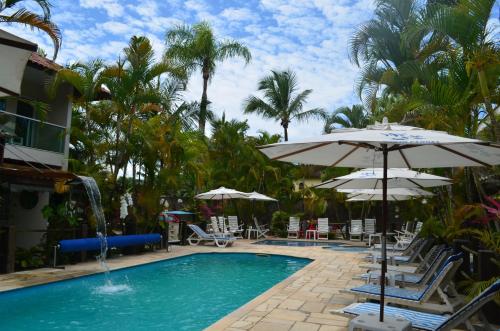 a swimming pool with chairs and umbrellas at Apart Hotel Porto Kanoas in Bertioga