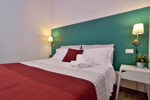 a bedroom with a large bed with a green wall at Modica Old Town Rooms in Modica