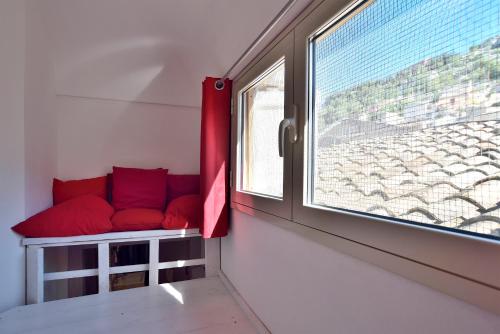 a red couch in a room with a window at Modica Old Town Rooms in Modica
