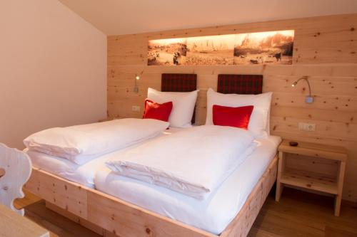 1 Schlafzimmer mit 2 Betten mit weißer Bettwäsche und roten Kissen in der Unterkunft Trafunshof natural living in Vols am Schlern