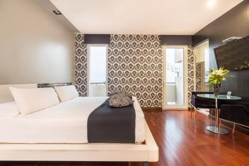 a bedroom with a large white bed and a table at Don Boutique Hotel Montevideo in Montevideo