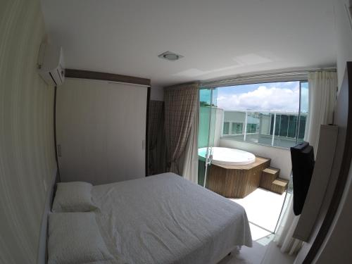 a bedroom with a bed and a tub and a window at Apartamento Cobertura Duplex in Bombinhas