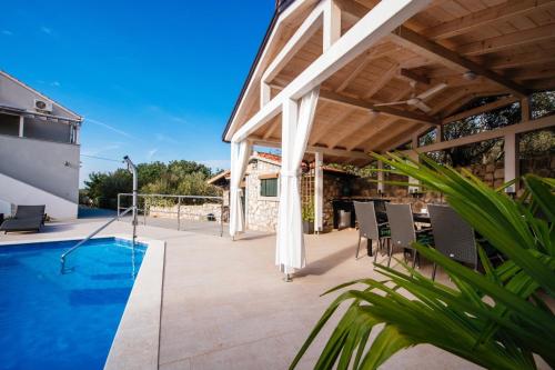 a patio with a table and chairs and a swimming pool at Holiday Home Ilovica - Mali Iž in Iž Mali