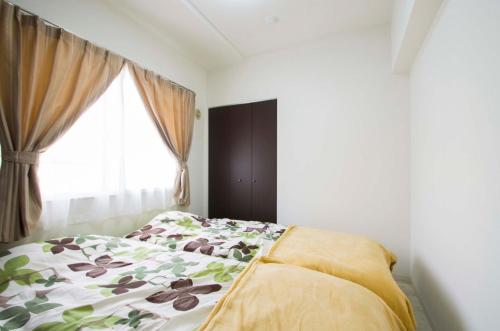 um quarto com uma cama com um edredão florido e uma janela em Sannand / Vacation STAY 2187 em Sapporo