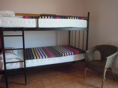 two bunk beds in a room with a chair at Albergue O Durmiñento in Sarria