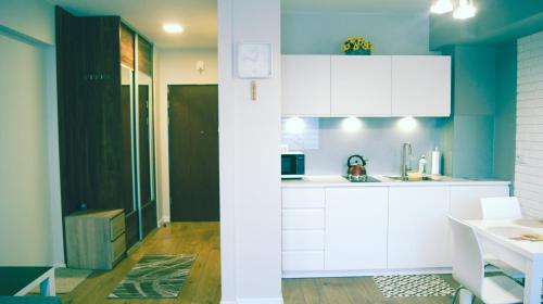 a kitchen with white cabinets and a blue wall at Apartamenty Topaz in Krynica Zdrój