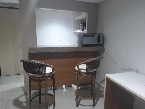 a kitchen with two chairs and a counter with a microwave at Marinas Flat 116 in Tambaú