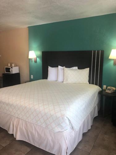 a bedroom with a large bed with white sheets and a green wall at Pinn Road Inn and Suites Lackland AFB and Seaworld in San Antonio