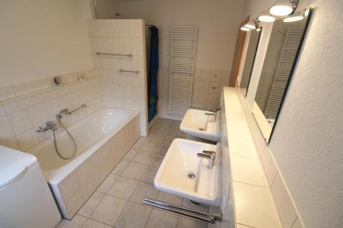 een badkamer met 2 wastafels, een bad en een toilet bij Mühlgarten in Immenstaad am Bodensee