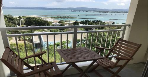 two chairs and a table on a balcony with the ocean at 220 Kouri Nakijin-son - Hotel / Vacation STAY 8715 in Nakijin