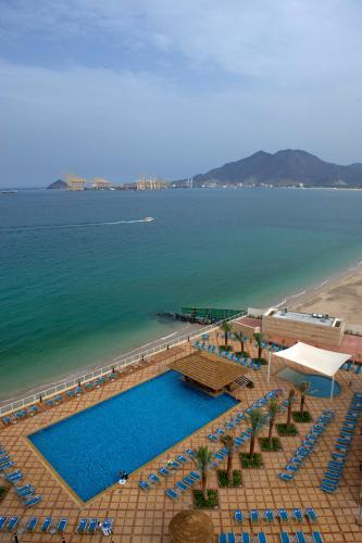 a large swimming pool next to a beach and the ocean at Oceanic Khorfakkan Resort & Spa in Khor Fakkan