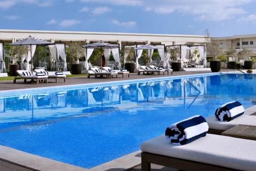 a large swimming pool with lounge chairs and umbrellas at Al Alamein Hotel in El Alamein