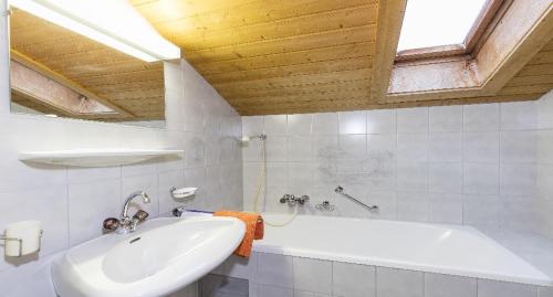 Baño blanco con bañera y lavamanos en Haus Ria, en Sölden