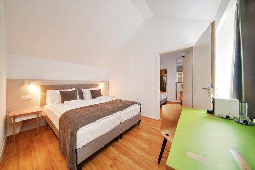 1 dormitorio con 1 cama y escritorio con TV en Fekete Sas Motel, en Esztergom
