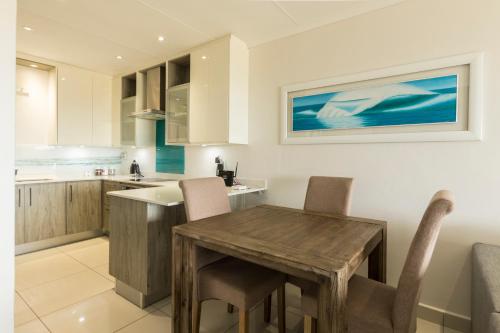 a kitchen with a wooden table and chairs at Modern Seaview Apartment in Summerstrand