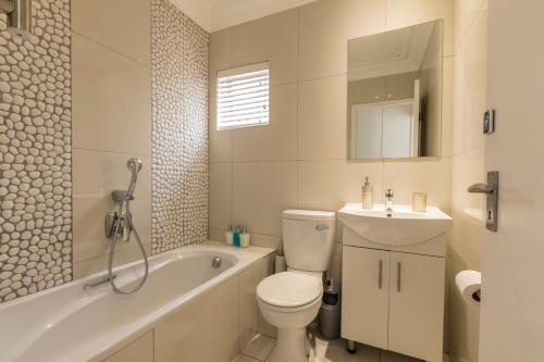 a bathroom with a toilet and a tub and a sink at Modern Seaview Apartment in Summerstrand