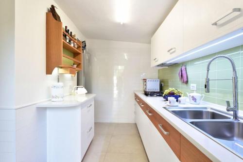 - une cuisine blanche avec évier et comptoir dans l'établissement VILLA MILVIO con accesso privato in spiaggia, à Tortolì