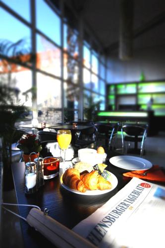 a table with a plate of croissants and orange juice at Hotel am Fjord in Flensburg