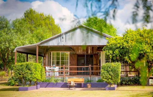 a house with a porch and a bench in front of it at Peppercorn Cabin in Broke