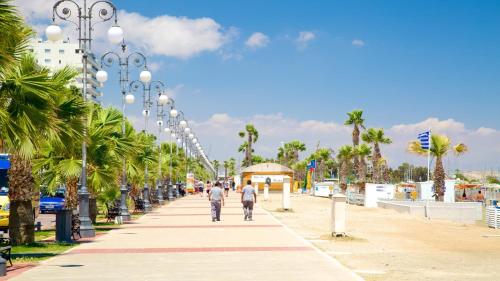two people walking down a sidewalk with palm trees at Camilla City apartment in Larnaka