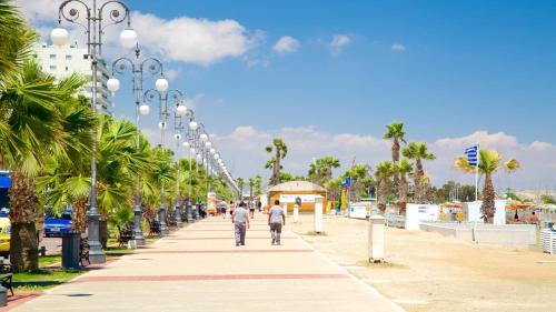 two people walking down a sidewalk with palm trees at Camilla City apartment in Larnaca