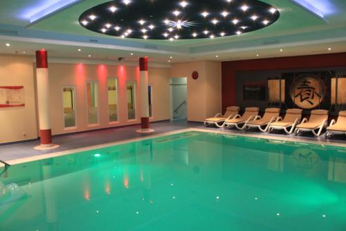 a swimming pool in a hotel with chairs and a ceiling at DAS HUDEWALD Hotel & Resort in Ueckeritz