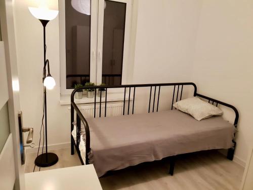 łóżko w pokoju z lampką i oknem w obiekcie Apartament Mikolowska 9 w mieście Katowice