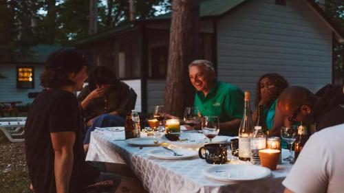a group of people sitting around a table with candles at The Elms Waterfront Cottages in Lake Luzerne