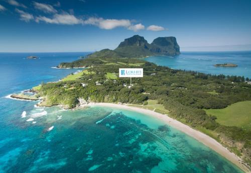 a beach with a view of the ocean and mountains at Lorhiti Apartments in Lord Howe