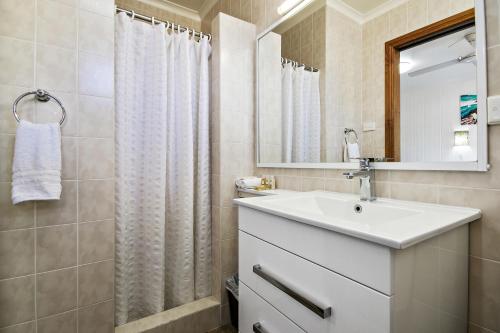 Lorhiti Apartments في جزيرة لورد هاو: حمام مع حوض أبيض ومرآة